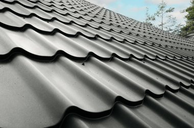Çelik çatı kaplaması olan kapalı bir çatı. Geleneksel metal kiremitler. Gri modüler fayans efekti çatı paneli. Çamur ya da beton levha olarak metalik kıvrımlı külotlar. Bina kapatıyor.