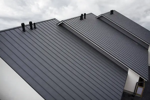 Dikişleri ve bağlayıcıları olan eski çatı paneli. İade eklemli klasik stil siyah metal panel. Kaburgalı, modern galvanize çelik çatı kaplaması. Falz çatısı. Bina kapatıyor.
