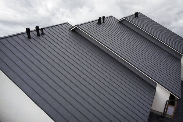Close-up house retro roof panel with standing seam and fasteners. Classic style black metal panel with rebate joint. Modern galvanized steel roofing sheet with ribs. Falz roofing. Building's covering