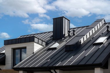 Dikişleri ve bağlayıcıları olan eski çatı paneli. İade eklemli klasik stil siyah metal panel. Kaburgalı, modern galvanize çelik çatı kaplaması. Falz çatısı. Bina kapatıyor.