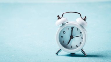 White alarm clock on blue turquoise  board.