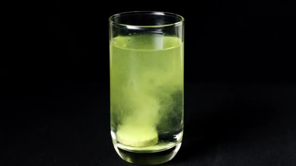 维生素C平板在透明的玻璃4K视频中溶解 在深色的背景上 在一杯水里面放一个泡沫片状溶液 药物在一杯4K的水溶液中溶解 — 图库视频影像