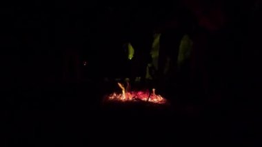 Kış gecesi kamp ateşi partisi 4K videosu. Alev alıyor ve sopayla ateşe daha fazla saman veriyor. Küçük şenlik ateşi 4K görüntüleri. Karanlık bir arka planda yanan şenlik ateşinin parlak alevi.