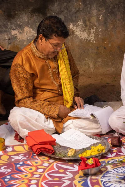 古いヒンズー教の聖職者が座って聖書を読んでいます ヒンズー教の結婚式の司祭は法会の要素の前に座っている 結婚式で伝統的なヒンズー教の礼拝儀式 ヒンドゥ教の僧 — ストック写真