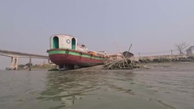 Güneydoğu Asya nehir kıyısı çalışan bir teknenin yakın çekim görüntüleri. Köprü ve şehir binası ile deniz manzarası yakın çekim. Güzel doğa ve nehir kıyısı görüntüleri. Kıyıda bakımsız bir gemi var..