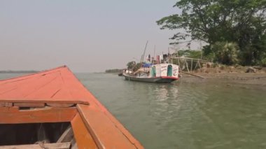 Hareket halindeki bir teknenin kırsal hayat görüntüleri. Güneydoğu Asya Riverbank ve Fisher 'ın limandaki balıkçı tekneleriyle 4K görüntüleri. Çalışan bir balıkçı teknesinden güzel doğa ve nehir kıyısı videosu.