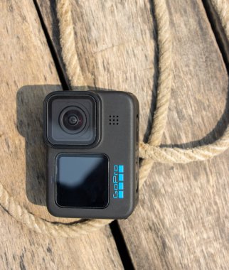 Dhaka, Bangladeş - 12 Mart 2023, GoPro 11 ahşap bir masada ve iple. Açık hava alanında profesyonel kamera yakın çekim görüntüsü. GoPro 11 siyah baskı kamera. İp ve ahşap yüzeyi var..