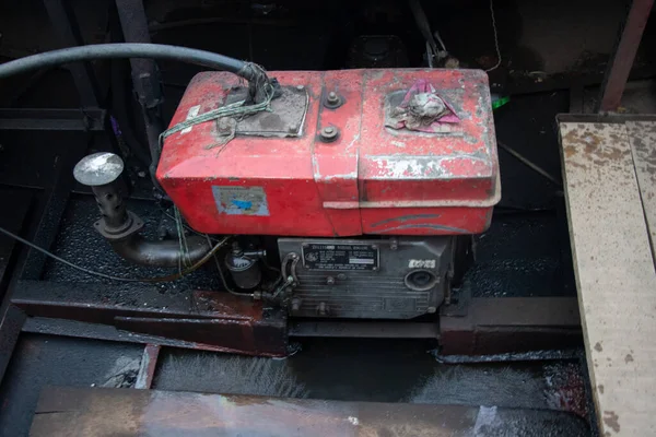 Yağ pası ve koyu yağlı yüzeyi olan eski bir tekne motoru. Tahta bir yüzeyde analog jeneratör ve tekne motoru. Eski ve paslı jeneratör yakın çekim. Güneydoğu Asya balıkçı teknesi ve yağ paslı tekne motoru.