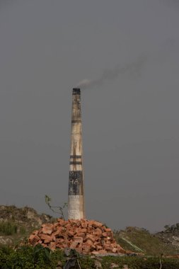 Kırsal kesimde uzun tuğla fırını. Yakın çekim. Tuğla ocağı ve tuğla yığını. Tuğla fırını havada çok fazla duman yaratıyor. Kırsal alanda hava kirliliği kavramı. Tuğla fabrikası..