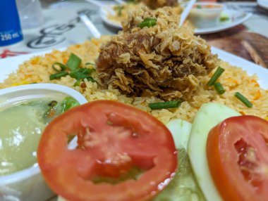 Lezzetli kızarmış pilav ve yakın çekim kızarmış tavuk. Karışık sebzeli restoran mutfağı, kızarmış pirinç, domates, salatalık ve kızarmış tavuk. Pirinç ve tavuğun gurme tarifi.