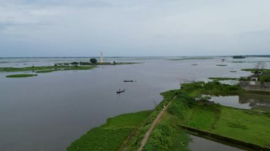 İçinde bir tekne olan bir Titas nehri, bir nehrin ortasında bir grup insan bir su kütlesi içinde bir teknede. Suyun ortasında kulesi olan küçük bir ada. Suda balık tutan biri..