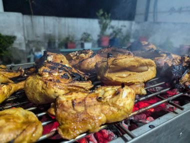 Grilling juicy chicken pieces over glowing charcoal in a cozy backyard during a warm evening gathering with friends and family enjoying delicious food and lively conversations clipart