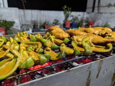 Sıcak bir yaz akşamı, canlı bir mahalle bahçesinde soslu tavuk ve canlı biber ızgarası.