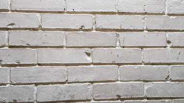 İnce dokuları ve düzensiz yüzeyleri gösteren yıpranmış beyaz tuğla bir duvar, muhtemelen kentsel bir ortamda, çeşitli tasarım projeleri için uygun rustik bir zemin oluşturur.