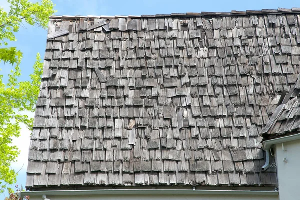 Wood shingle roof in poor repair. Wood shingles are thin, tapered pieces of wood primarily used to cover roofs and walls of buildings to protect them from the weather. susceptible to fire and costly