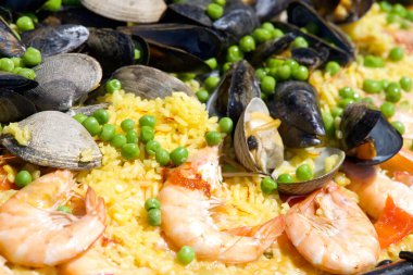 Deniz tarakları, kaslar, karides pilavı ve bezelyeler dev bir açık hava tavasında pişiyor..