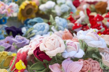 Kapatın el yapımı tığ işi pastel pembe gül çiçekleri çeşitli bahar renklerinde tığ işi çiçeklerle çevrili..