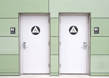 Binanın dışındaki umumi tuvalet kapıları, beton yol. Kapılarında tuş takımı kilitleri olan Unisex tuvaletleri..