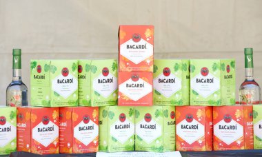 Oakland, CA - 10 Eylül 2023: Mojito ve Bahama Mama aromalı bir masaya yerleştirilmiş Bacardi romu kutuları. Arkadaki kahverengi tuval. Açık bar kurulumu.