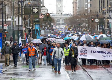 San Francisco, CA - 03 Mart 2024: Pazar Caddesi 'ndeki Anti-Semitizmle Mücadele Merkezi' nin kimliği belirsiz katılımcıları. Yağmurda yürürken.
