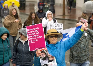 San Francisco, CA - 03 Mart 2024: Pazar Caddesi 'ndeki Anti-Semitizmle Mücadele Merkezi' nin kimliği belirsiz katılımcıları. Yağmurda yürürken.