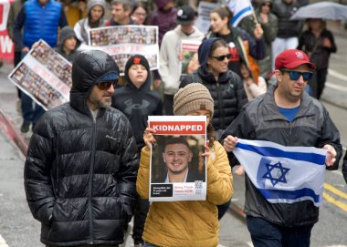 San Francisco, CA - 03 Mart 2024: Pazar Caddesi 'ndeki Anti-Semitizmle Mücadele Merkezi' nin kimliği belirsiz katılımcıları. Yağmurda yürürken.