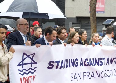 San Francisco, CA - 03 Mart 2024: Politikacılar ve tanımlanamayan katılımcılar Pazar Caddesi 'ndeki Anti-Semitizm karşıtı bir yürüyüşe katıldılar. Yağmurda yürürken.