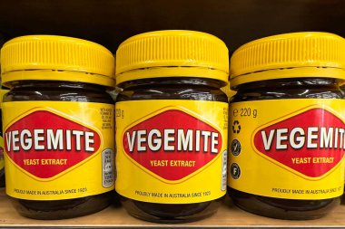Oakland, CA - July 1, 2022: Grocery store shelf with jars of Vegemite brand Yeast Extract, a thick black Australian food spread made from leftover brewers yeast extract with vegetables and spice  clipart