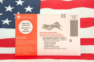 Alameda, CA - Nov 6, 2022: Midterm election ballots sent out to all registered voters in California. American flag in background. clipart