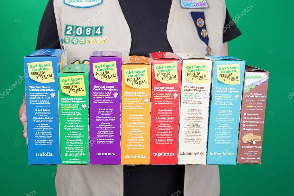 Alameda, CA - March 04, 2022: Cadette Girl Scout holding boxes of Girl Scout cookies. Girl Scout cookie sales help girls learn marketing and money management skills.