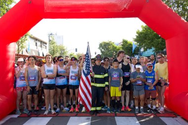 Alameda, CA - July 4, 2024: Participants line up at the starting line for the Alameda Mayors 4th of July R.A.C.E. A five km run and walk through Alameda.  clipart