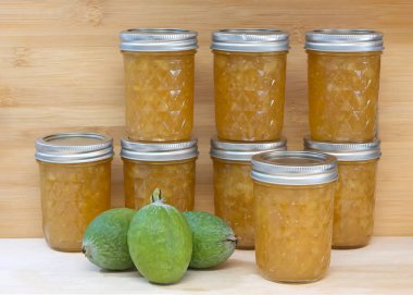 Acca sellowiana Burret ya da Pineapple Guava olarak da bilinen taze Feijoa sellowiana ile taze ev yapımı reçel kavanozlarına yakın durun. Ahşap arka planlı açık tahta masa.