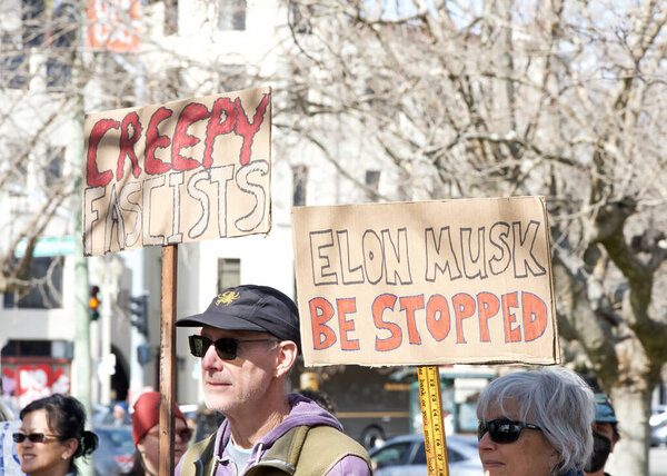 Oakland, CA - Feb 17, 2025: Unidentified participants in a Not My Presidents Day protest and march and rally from the Fruitvale Bart to Lake Merritt. Holding signs at Lake Merritt Rally.