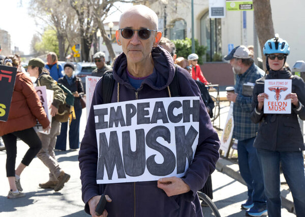 Berkeley, CA - March 1, 2025: Protestors hoding signs blocking traffic in front of a Tesla showroom. Denouncing Musk and calling for a boycott as a result of his recent actions on Capitol Hill