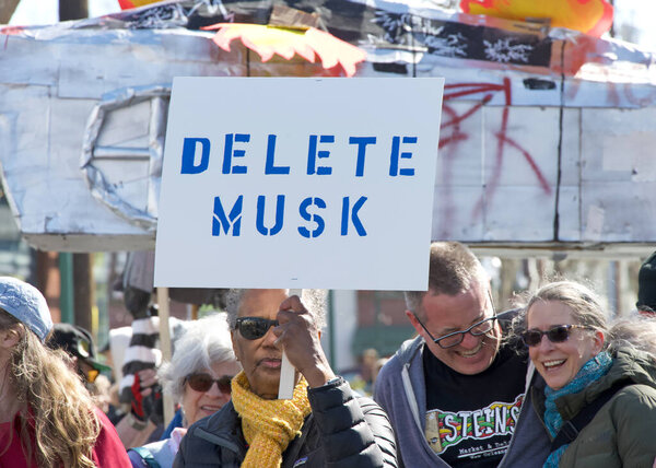 Berkeley, CA - March 1, 2025: Protestors hoding signs blocking traffic in front of a Tesla showroom. Denouncing Musk and calling for a boycott as a result of his recent actions on Capitol Hill.