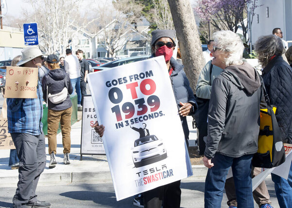 Berkeley, CA - March 1, 2025: Protestors hoding signs blocking traffic in front of a Tesla showroom. Denouncing Musk and calling for a boycott as a result of his recent actions on Capitol Hill.