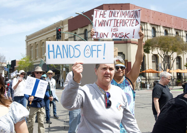 Alameda, CA - April 5, 2025: Unidentified participants in a HANDS OFF, Remove, Reverse, Reclaim protest, marching down Park Street. Protesting the current administration.