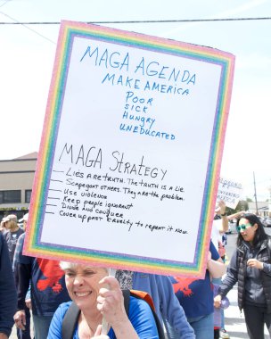 Alameda, CA - 14 Haziran 2025: Kimliği belirsiz kişiler, Kings 'e Hayır Yürüyüşü yürüyüşü' nde şehir sokaklarında yürüyor. Trafik kurallarına uyarak kaldırımlarda yürüyor ve yaya geçitlerinde bekliyor..