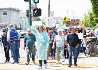 Alameda, CA - 14 Haziran 2025: Kimliği belirsiz kişiler, Kings 'e Hayır Yürüyüşü yürüyüşü' nde şehir sokaklarında yürüyor. Trafik kurallarına uyarak kaldırımlarda yürüyor ve yaya geçitlerinde bekliyor..