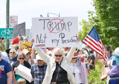 Alameda, CA - 14 Haziran 2025: Kimliği belirsiz kişiler, Kings 'e Hayır Yürüyüşü yürüyüşü' nde şehir sokaklarında yürüyor. Trafik kurallarına uyarak kaldırımlarda yürüyor ve yaya geçitlerinde bekliyor..