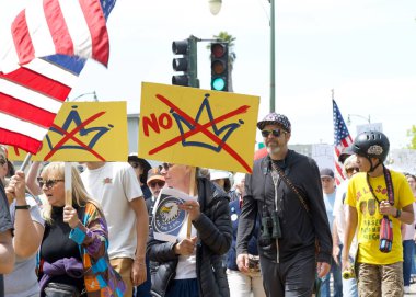 Alameda, CA - 14 Haziran 2025: Kimliği belirsiz kişiler, Kings 'e Hayır Yürüyüşü yürüyüşü' nde şehir sokaklarında yürüyor. Trafik kurallarına uyarak kaldırımlarda yürüyor ve yaya geçitlerinde bekliyor..