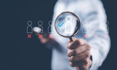 İş adamı, İnsan Kaynakları Yönetimi HRM konseptinde iş arıyor. İş adamı, insan gelişimi ve adam toplama kavramı için insan simgelerini aramak için büyüteç tutuyor.