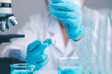 Bilim insanları biyokimya alanında deneyler yapıyor, araştırıyor ve analiz ediyor. Bir aşı geliştirmek için mikroskop ile işbirliği yapıyorlar..