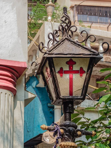 12 03 2022 Red Stained Glass Cross on portuguesas antiguas lamp in front of Holy Cross Oratory Matharpacady Village Mazgaon, Mumbai  Maharashtra India