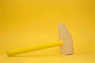 Sarı arka planda tahta çekiç.