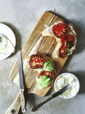 Domatesli kruvasan ve doğrama tahtasında avokado.