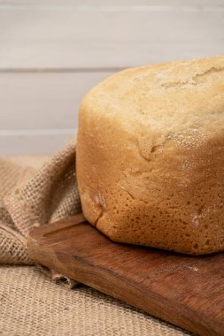 Ahşap bir masada ev ekmeği makinesiyle yapılan ekmeğin detaylı görüntüsü. Dikey yönelim.