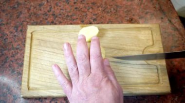 Bir şef, tahta kesme tahtasına patates ya da büyük bir mirepoix kesiyor..