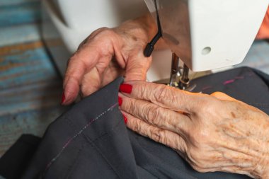 Dikiş makinesine pantolon diken bir terzinin elleri..