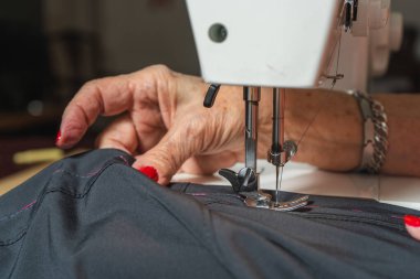 Dikiş makinesine pantolon diken kadın bir terzinin elleri..
